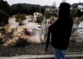 A man observes several cars being swept away by the water, after floods preceded by heavy rains caused the river to overflow its banks in the town of Alora, Malaga, Spain, Tuesday, Oct. 29, 2024. (AP Photo/Gregorio Marrero)