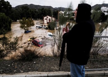 A man observes several cars being swept away by the water, after floods preceded by heavy rains caused the river to overflow its banks in the town of Alora, Malaga, Spain, Tuesday, Oct. 29, 2024. (AP Photo/Gregorio Marrero)