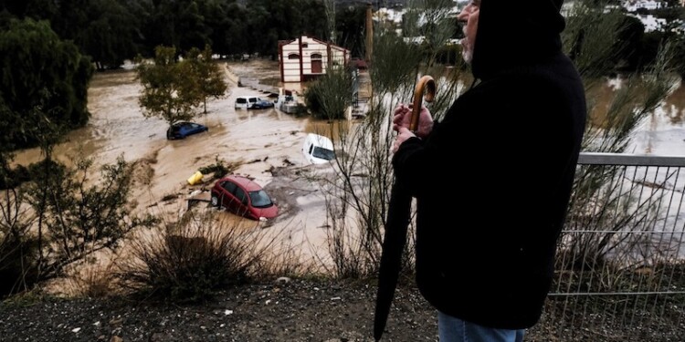 A man observes several cars being swept away by the water, after floods preceded by heavy rains caused the river to overflow its banks in the town of Alora, Malaga, Spain, Tuesday, Oct. 29, 2024. (AP Photo/Gregorio Marrero)