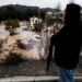 A man observes several cars being swept away by the water, after floods preceded by heavy rains caused the river to overflow its banks in the town of Alora, Malaga, Spain, Tuesday, Oct. 29, 2024. (AP Photo/Gregorio Marrero)